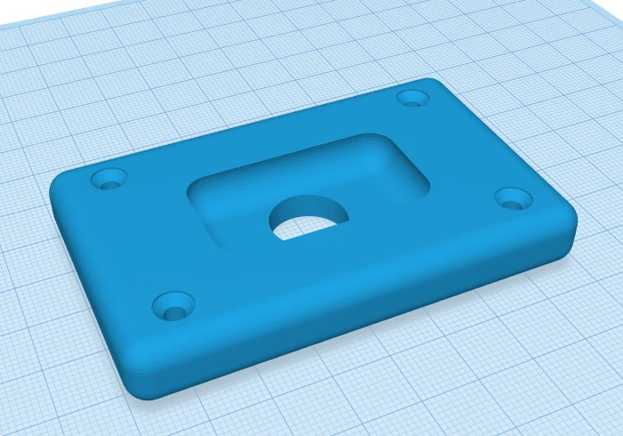 After grouping: a blue mounting plate with four countersunk screw holes, a rounded pocket and a hole straight through the middle.