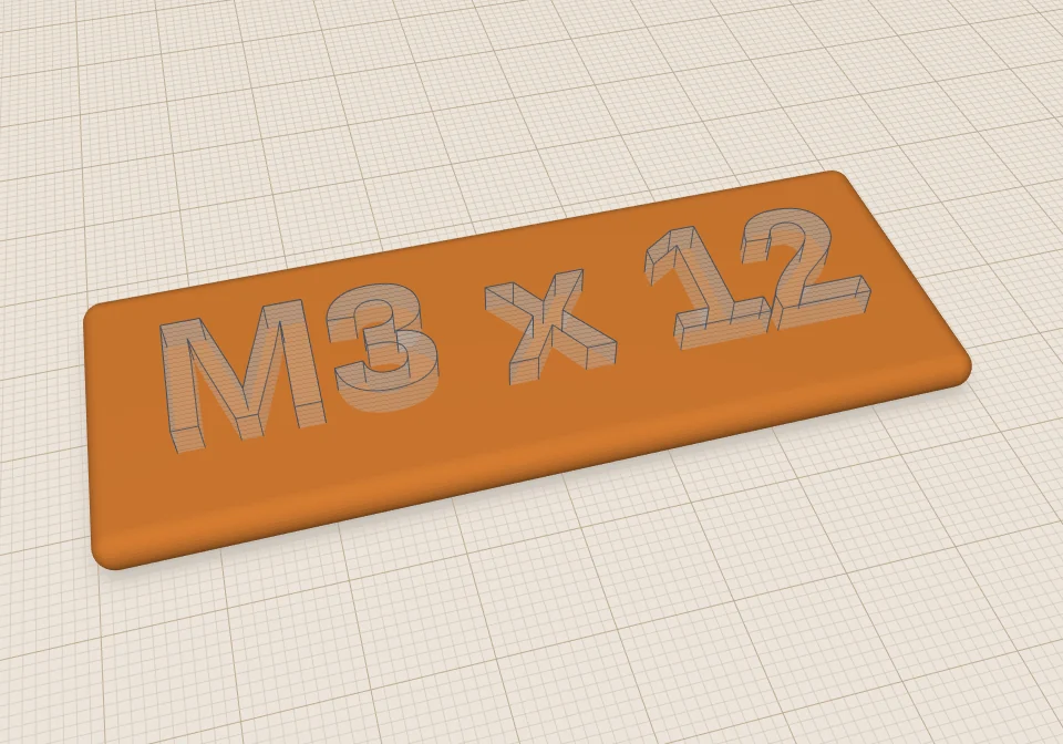An orange plate with the text M3 x 12 as a see-through hole shape sitting in its top.