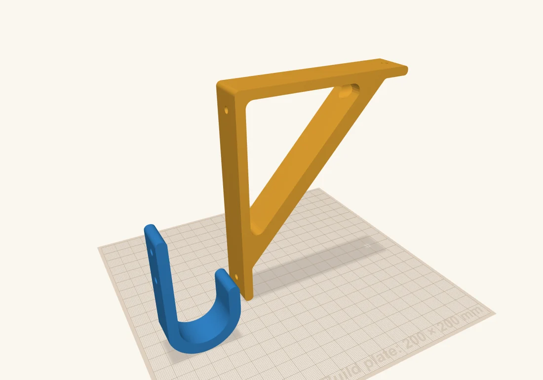 A blue wall hook and a yellow shelf bracket standing upright on the build plate, the way they hang on a wall.